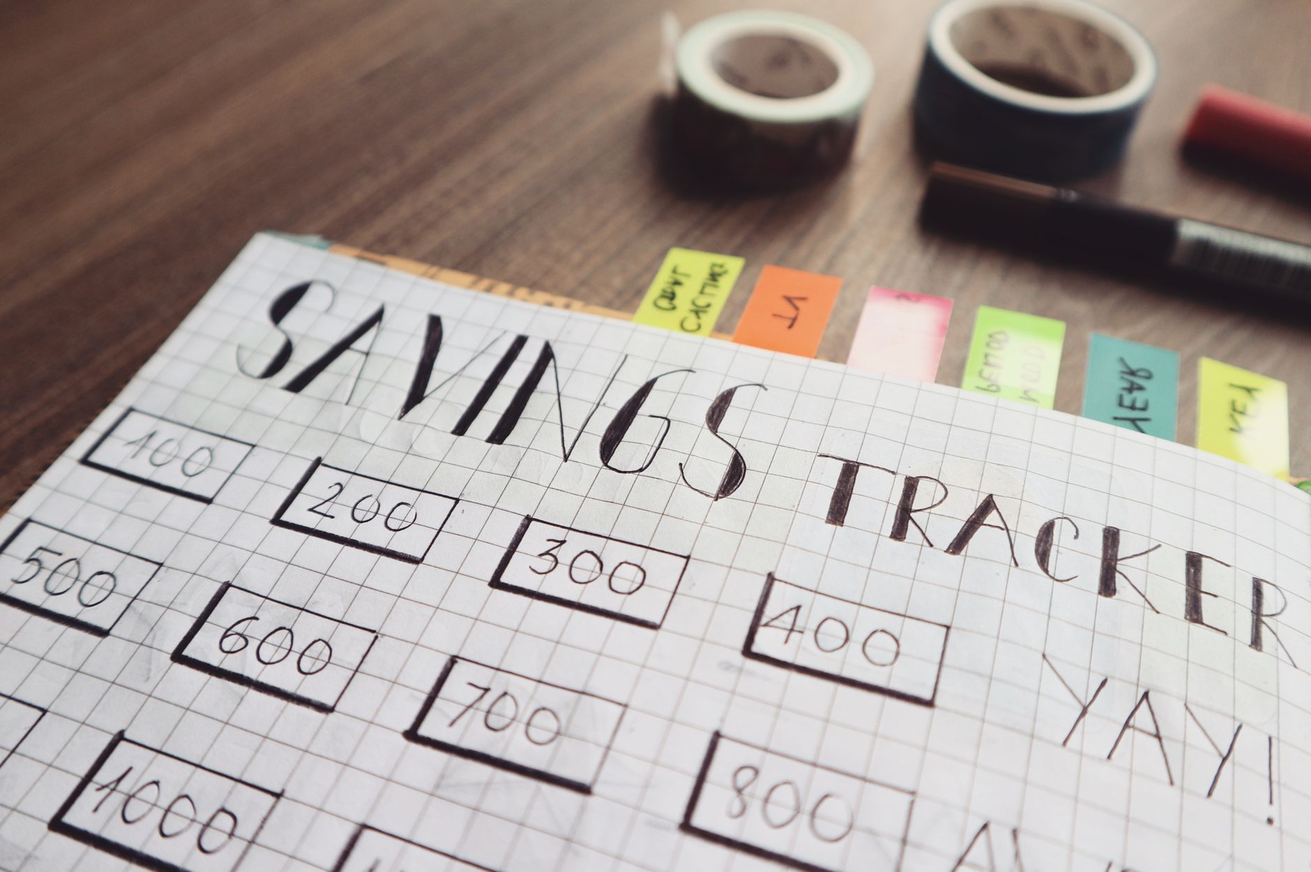 A notebook with a hand-drawn savings chart and a pen on top